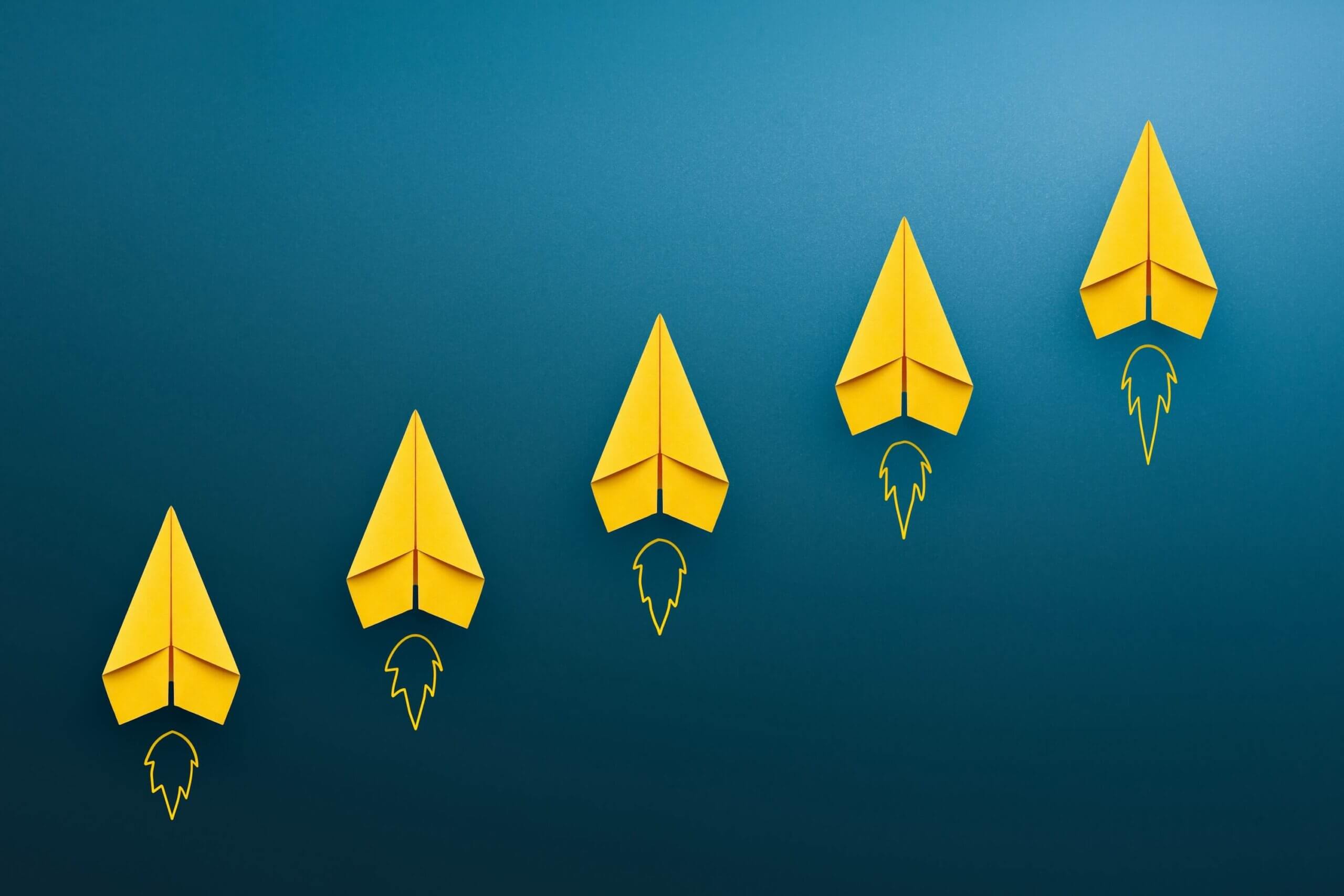 Row of yellow paper planes signify a launch about the article with how Leadership Training can impact productivity in a team.
